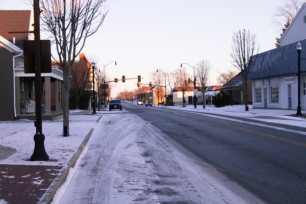 Cars parked along a wide street with snow along the edges